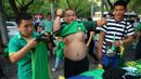 Suporter klub Beijing Guoan FC mencoba atribut klub yang dijual pedagang kaki lima di sekitar area stadion.(EPA/Wu Hong)