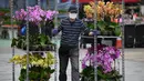 <p>Seorang pedagang membawa bunga yang akan dijual pada hari pembukaan pasar bunga di Hong Kong (16/1/2023). Menjelang Tahun Baru Imlek yang menandai tahun Kelinci pasar bunga di Hong Kong mulai ramai di kunjungi pengunjung. (AFP/Peter Parks)</p>