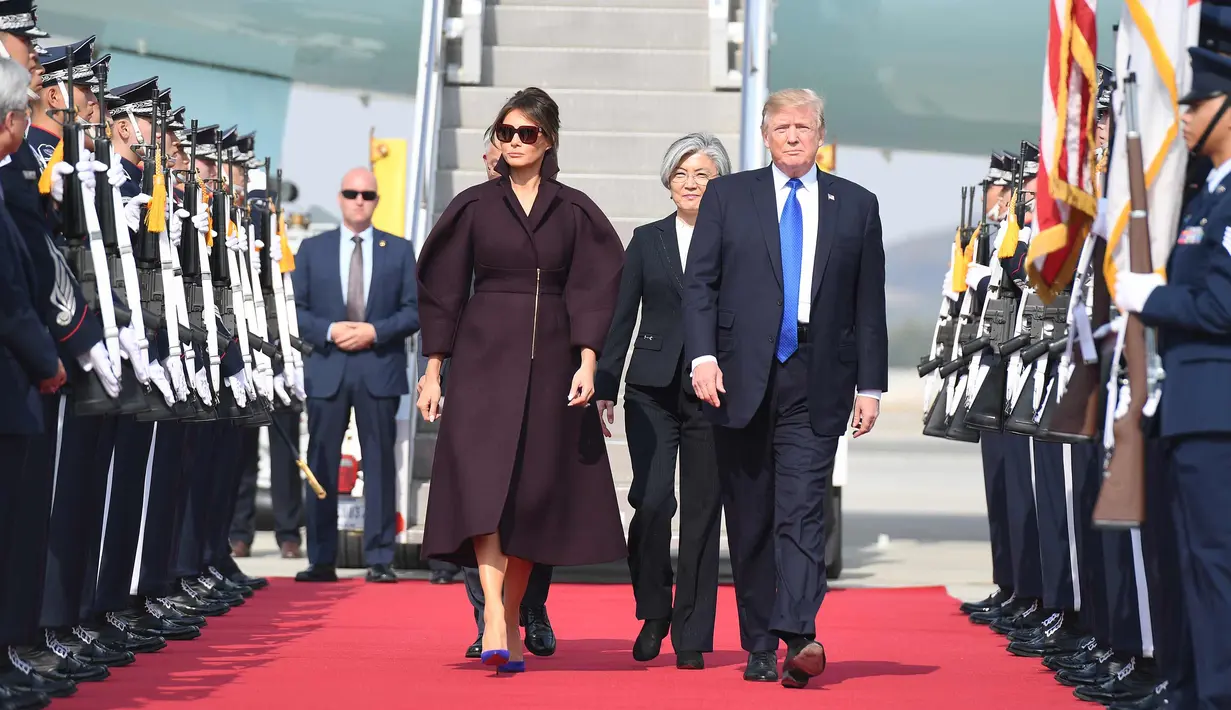 Presiden Donald Trump dan Melania berjalan melintasi barisan tentara saat tiba di Pangkalan Udara Osan, Pyeongtaek, Korea Selatan, (7/11). (AP Photo / Andrew Harnik)