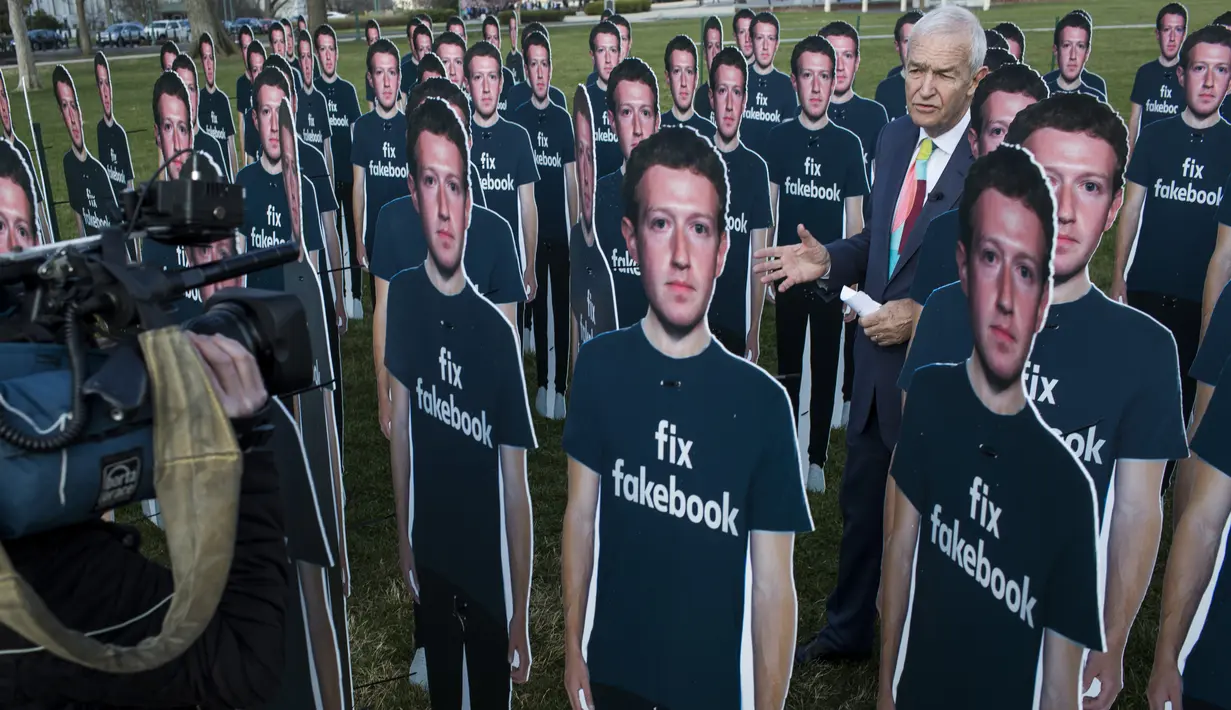 Awak media mengambil berita di 100 di dekat potongan karton CEO Facebook Mark Zuckerberg yang berjejer di halaman Capitol AS di Washington DC (10/4). (Zach Gibson / Getty Images / AFP)