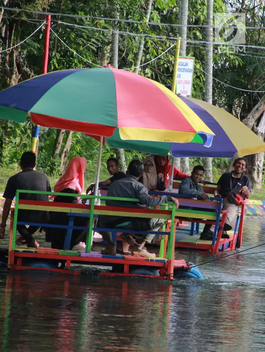 Wisatawan menaiki perahu apung di Wisata Air Toino, Desa Talulobutu, Kecamatan Tapa, Kabupaten Bone Bolango, Gorontalo, Sabtu (30/3). Wisata air yang kian viral di media sosial ini akan semakin ramai pada saat akhir pekan. (Liputan6.com/Arfandi Ibrahim)