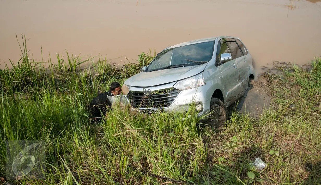 Petugas memasangkan rantai penarik untuk mengevakuasi mobil yang terperosok di saluran Inspeksi Kalimalang, Jabar, Minggu (7/5). Penyebab kecelakaan itu diduga pengemudi mengantuk dan berusaha menghindari pengendara motor. (Liputan6.com/Gempur M Surya)