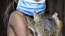 Gadis suku Tikuna berpose mengenakan masker di tengah kekhawatiran virus corona Covid-19 di Leticia, Departemen Amazonas, Kolombia pada 8 Juni 2020. Kasus virus corona ini meningkatkan kekhawatiran akan resiko penyebaran ke masyarakat adat yang rentan dan berada di pedalaman. (Tatiana de NEVO/AFP)
