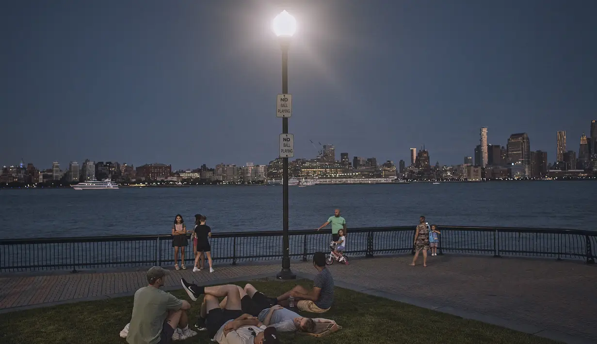 Orang-orang menghabiskan waktu di taman saat senja selama gelombang panas musim panas di Hoboken, NJ, Kamis (21/7/2022). Gelombang panas diperkirakan akan berlanjut hingga akhir pekan. (AP Photo/Andres Kudacki)