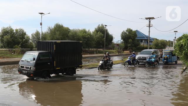 <span>Sejumlah kendaraan melintasi banjir rob di kawasan Pelabuhan Perikanan Samudera Nizam Zachman, Muara Baru, Jakarta, Sabtu (6/11/2021). Banjir rob tersebut disebabkan karena naiknya permukaan air laut. (Liputan6.com/Herman Zakharia)</span>