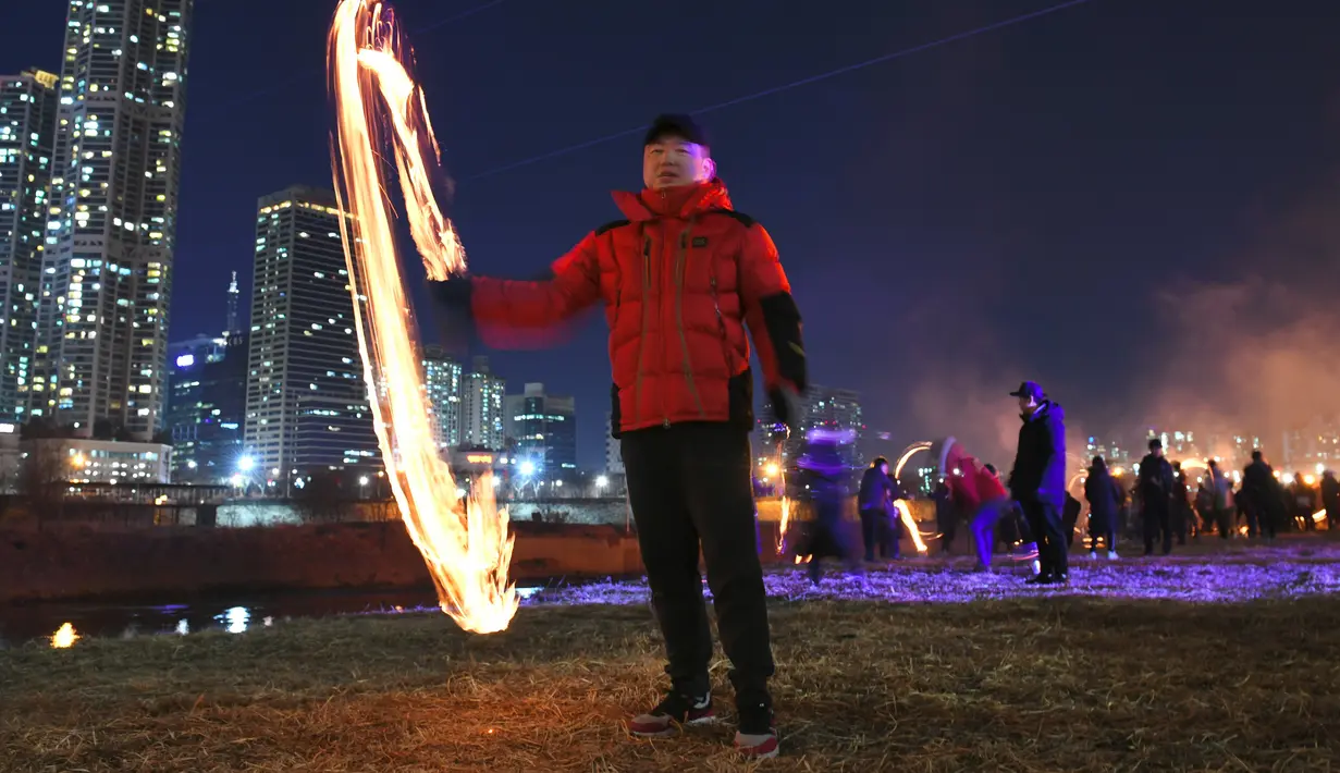 Seorang pria memutar kaleng arang yang terbakar selama acara "Jeongwol Daeboreum" atau (Perayaan Bulan Purnama) pertama tahun baru Imlek di taman tepi sungai di Seoul (17/2). (AFP Photo/Jung Yeon-je)