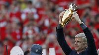 Pelatih Arsenal, Arsene Wenger, mengangkat trofi mini  saat perpisahan di Stadion Emirates (6/5/2018). Selama 22 tahun membesut Arsenal, Wenger telah mempersembahkan 17 gelar dan 704 Kemenangan. (AFP/Ian Kington)