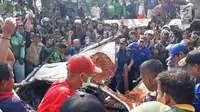 Warga berkerumun menyaksikan proses evakuasi bangkai mobil kecelakaan maut yang hancur tertindih badan truk muatan tanah di Karawaci, Tangerang, Kamis (1/8/2019). Sopir truk yang menimpa mobil dan menewaskan 4 orang itu kabur setelah kecelakaan maut terjadi. (Liputan6.com/Pramita Tristiawati)