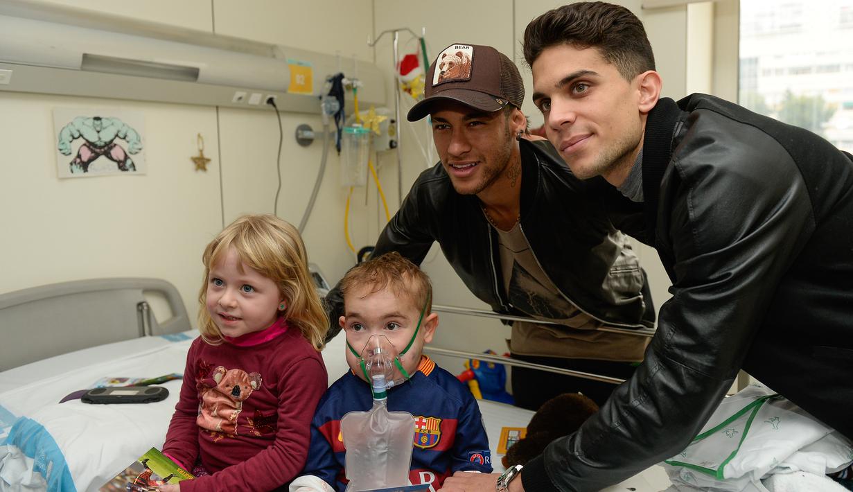 Pemain Barcelona, Marc Bartra (kiri) dan Neymar berpose dengan pasien anak saat melakukan kunjungan amal di Rumah Sakit Vall d' Hebron, Barcelona, Senin (4/1/2016). (AFP PHOTO / Josep LAGO)
