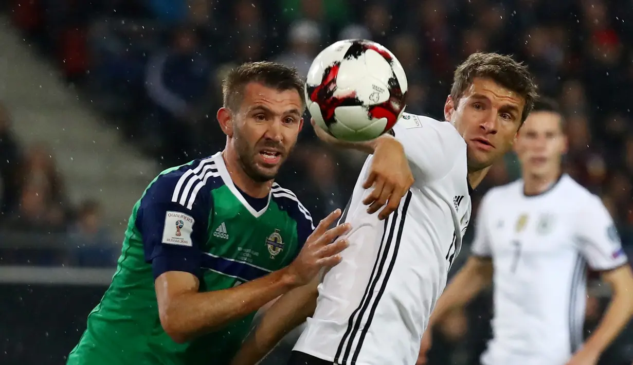 Striker Jerman, Thomas Muller (kanan), dijaga ketat pemain Irlandia Utara, Gareth McAuley, pada laga Grup C Kualifikasi Piala Dunia 2018 zona Eropa, di HDI-Arena, Hanover, Rabu (12/10/2016) dini hari WIB. (Reuters/Kai Pfaffenbach)