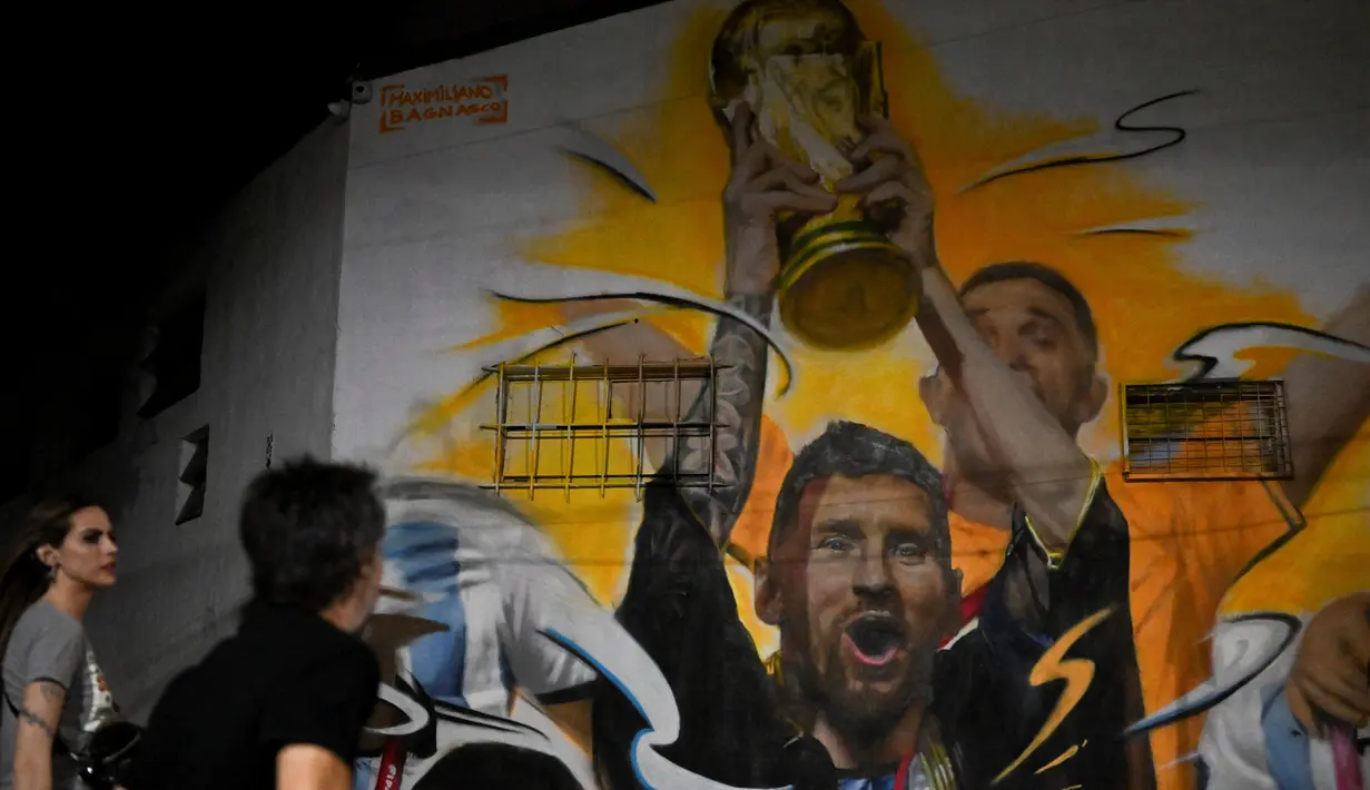 <p>Warga melihat Mural yang menggambarkan kapten dan penyerang Argentina Lionel Messi mengangkat Trofi Piala Dunia 2022 di samping rekan satu timnya setelah memenangkan turnamen Piala Dunia Qatar 2022 di Buenos Aires pada 22 Desember 2022. Argentina berhasil meraih juara setelah mengalahkan Prancis di babak final. (AFP/Luis Robayo)</p>