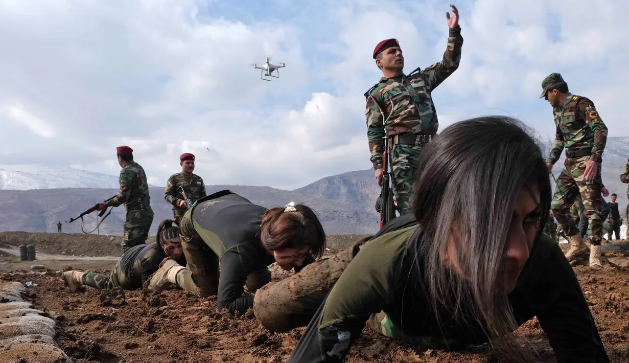 Pasukan perempuan Peshmerga merayap di tanah saat berlatihan dalam upacara kelulusan di Kota Soran, Irak, Rabu (12/2/2020). Latihan militer pasukan bersenjata Kurdi tersebut dilakukan sekitar 100 kilometer timur laut ibu kota otonomi wilayah Kurdi di Irak, Arbil. (SAFIN HAMED/AFP)