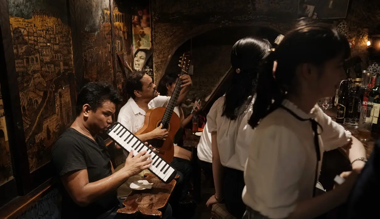 Dua musisi menghibur pengunjung di bar kecil di Golden Gai di distrik Shinjuku Tokyo (28/7/2019). Lebih dari 200 bar kecil bergaya klub dan restoran di area ini. (AP Photo / Jae C. Hong)