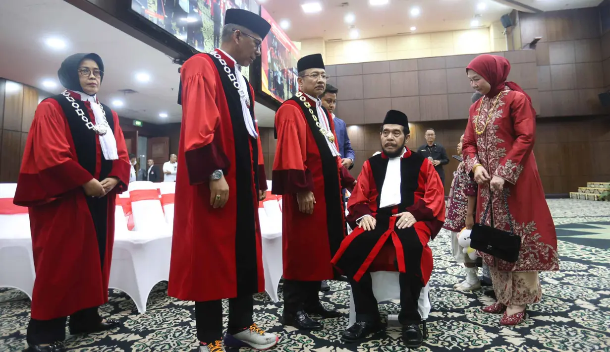 Setelah menyelesaikan seluruh rangkaian prosesi purnabakti, Anwar Usman berpamitan dengan para hakim aktif dan berjalan menuju pintu keluar. Tampak dalam foto, Anwar Usman (kedua kanan duduk) beristirahat usai mengikuti prosesi wisuda purnabakti di Ruang Sidang Mahkamah Konstitusi (MK), Jakarta, Senin (13/4/2026). (Kapanlagi.com/Budy Santoso)