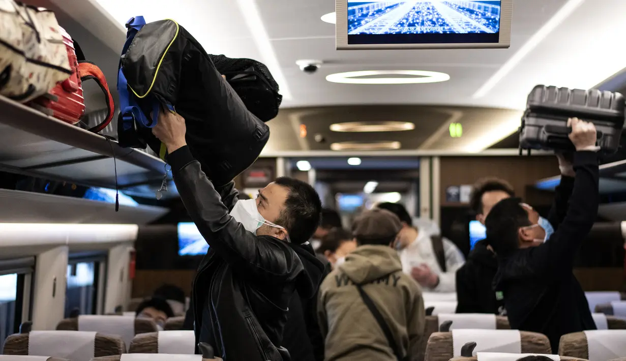 Penumpang dengan mengenakan masker menaiki kereta api menuju Beijing di stasiun kereta Wuhan, provinsi Hubei, Rabu (15/4/2020). Usai status lockdown dicabut, orang-orang yang sebelumnya berada di Wuhan perlahan mulai meninggalkan kota, salah satu tujuannya adalah Beijing.  (NOEL CELIS/AFP)
