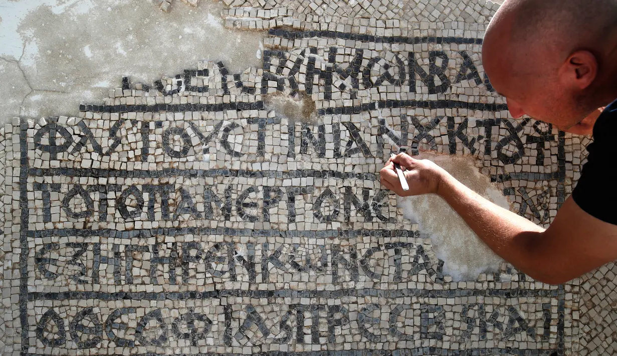 Arkeolog meneliti lantai mosaik berusia 1.500 tahun di Museum Rockefeller, Yerusalem, Rabu (23/8). Prasasti bertuliskan aksara dan bahasa Yunani kuno ditemukan selama pengerjaan pemasangan kabel komunikasi di Kota Tua Yerusalem. (AHMAD GHARABLI/AFP)