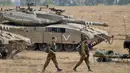 <p>Tentara Israel berjalan melewati tank di dekat perbatasan Gaza-Israel, Jumat (19/10). PM Benjamin Netanyahu berjanji bakal mengambil tindakan tegas apabila warga Palestina masih terus melancarkan serangan ke wilayah Israel. (AP Photo/Ariel Schalit)</p>
