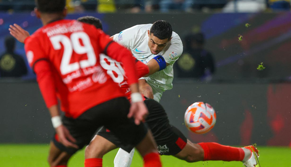 Pemain Al Nassr, Cristiano Ronaldo (kanan), menendang bola ke gawang Al Riyadh dalam laga pekan ke-16 Saudi Pro League 2023/2024 yang digelar di Al Awwal Park, Sabtu (9/12/2023) dini hari WIB. Cristiano Ronaldo saat ini memimpin perebutan gelar top skor Saudi Pro League 2023/2024 dengan catatan 16 gol. (AFP/Fayez Nureldine)
