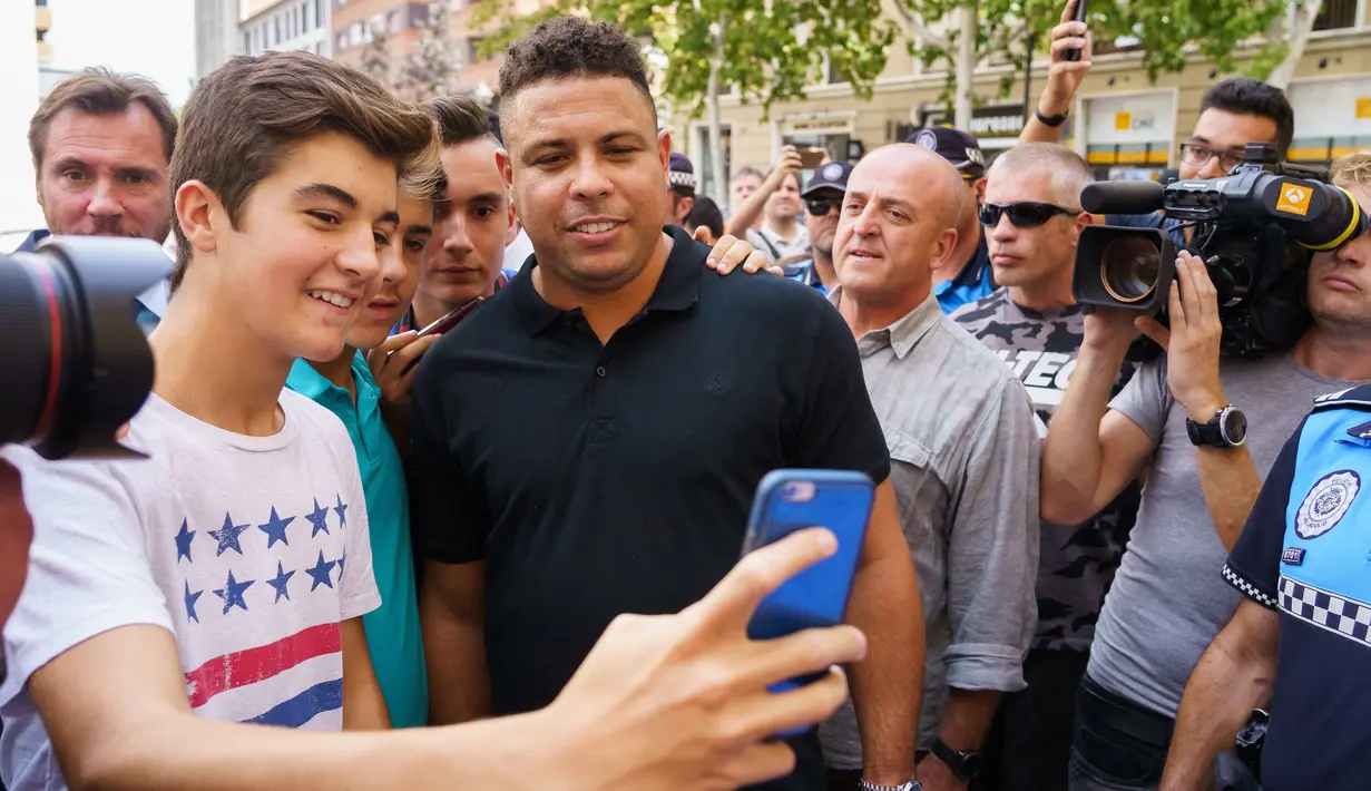 Fans berselfie dengan legenda sepak bola Brasil Ronaldo setelah konferensi pers di Valladolid, Spanyol, (3/9). Alasan Ronaldo membeli saham mayortas Valladolid untuk membangkitkan kembali klub yang sempat terdegradasi tersebut. (AFP Photo/Cesar Manso)