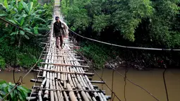 Seorang kakek berjalan di atas jembatan bambu yang menghubungkan Kampung Bambon, Jakarta Selatan dan Kelapa Dua Depok, Depok, Jumat (13/3/2015). (Liputan6.com/Yoppy Renato)
