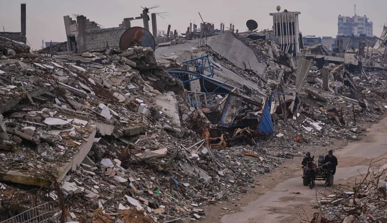 Data Shelter Cluster Gaza yang dikutip UNRWA mencatat, hujan deras dan angin kencang akibat tekanan cuaca rendah pada 10–17 Desember 2025 menyebabkan 17 bangunan runtuh serta merusak lebih dari 42.000 tenda dan hunian darurat, baik sebagian maupun total. Tampak dalam foto, warga Palestina berjalan di sepanjang jalan yang dikelilingi bangunan-bangunan yang hancur akibat serangan udara dan darat Israel di lingkungan Sheikh Radwan, Kota Gaza, Selasa, 30 Desember 2025. (AP Photo/Abdel Kareem Hana)
