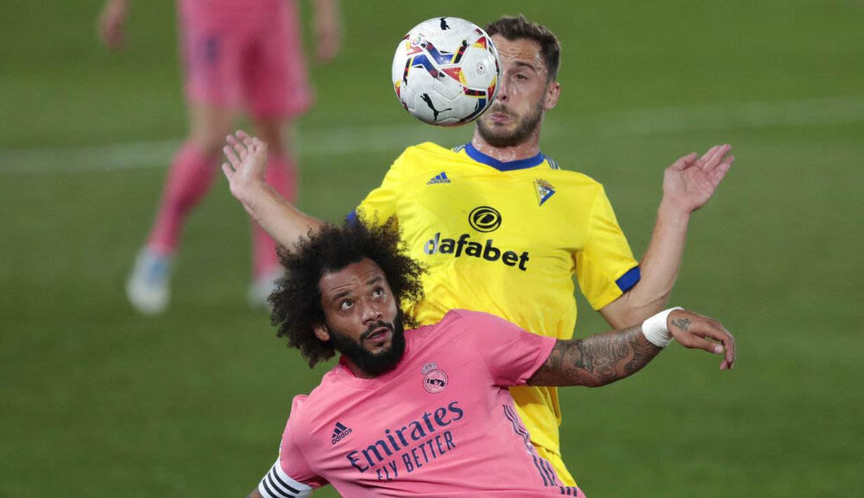 Bek Real Madrid, Marcelo, berebut bola dengan pemain Cadiz, Filip Malbasic, pada laga Liga Spanyol di Stadion Alfredo Di Stefano, Minggu (18/10/2020). Real Madrid takluk dengan skor 1-0. (AP/Bernat Armangue))