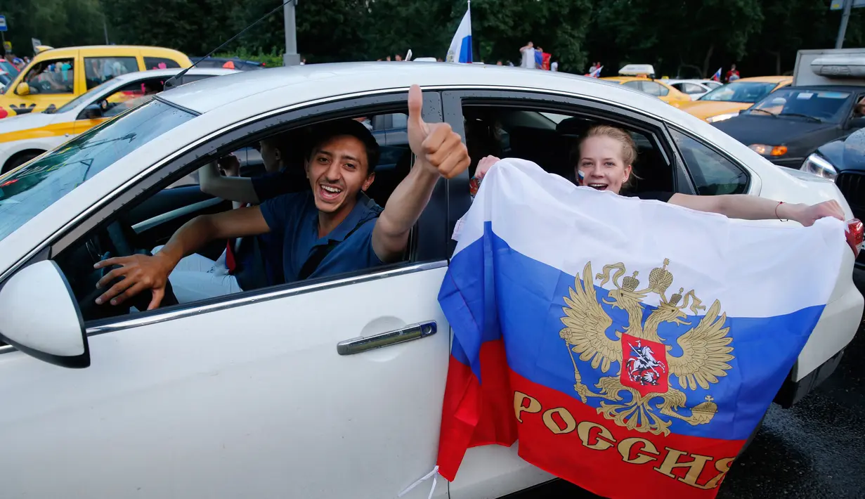 Suporter Rusia berpesta merayakan keberhasilan negaranya mengalahkan Spanyol pada laga 16 besar Piala Dunia di Moskow, Minggu (1/7/2018). Rusia untuk pertama kalinya lolos ke babak perempatfinal. (AFP/Maxim Zmeyev)