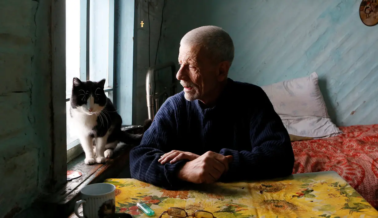 Mikhail Baburin (66) berbicara dengan kucing peliharaannya, Marquis, di rumahnya di desa Mikhailovka di Siberia, 5 Desember 2016. Selama 10 tahun terakhir, Baburin tinggal sendirian di desa yang letaknya sangat terpencil. (REUTERS/Ilya Naymushin)