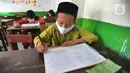 Murid kelas V mengikuti ujian Penilaian Akhir Semester (PAS) tahun pelajaran 2020/2021 di Madrasah Ibtidayah (MI) Assu'ada di Pancoran Mas, Depok, Jawa Barat, Selasa (1/12/2020). Ujian dilaksanakan dengan menerapkan protokol kesehatan dalam kelas. (merdeka.com/Arie Basuki)