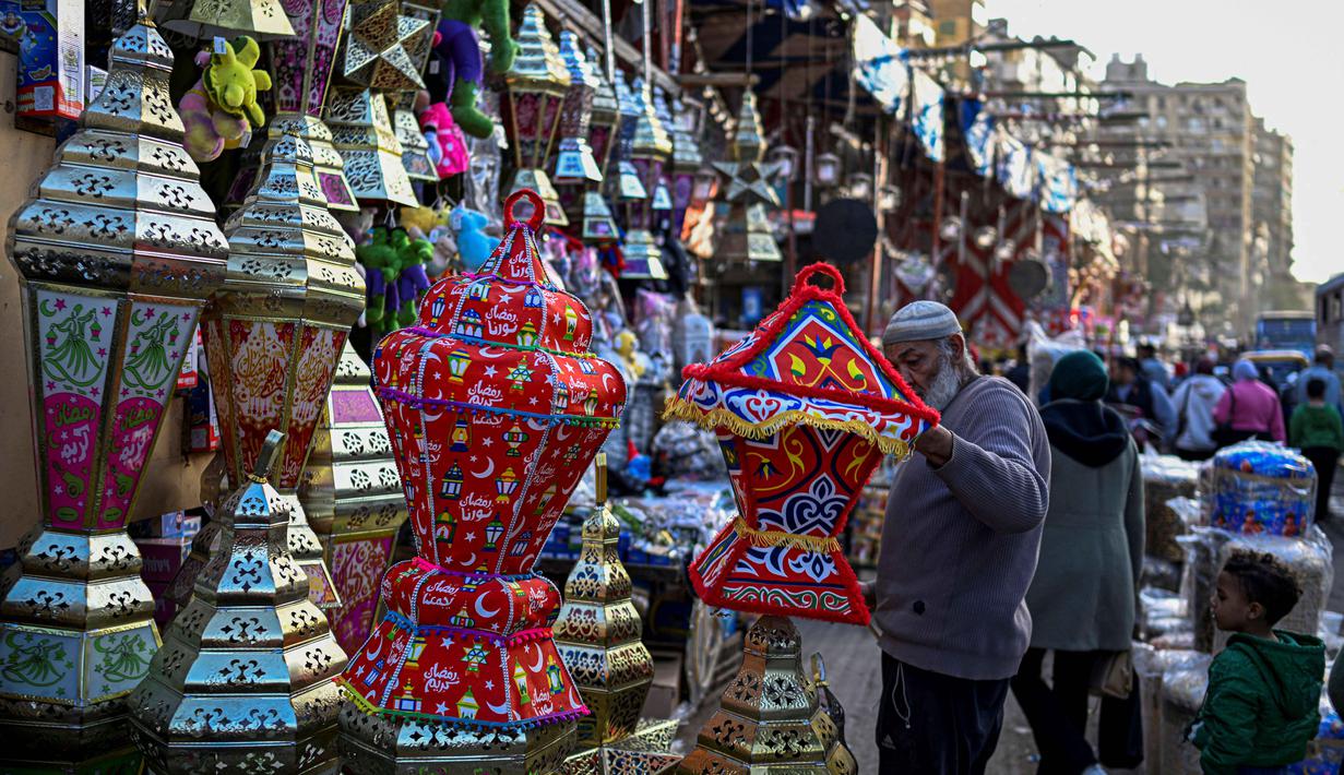 Fanous (Lentera Ramadan) menjadi simbol paling ikonik. Tampak dalam foto, seorang pedagang Mesir merangkai lampion tradisional, yang dikenal secara lokal sebagai 'Fanous Ramadan', di pusat Kairo pada Kamis 12 Februari 2026. (Khaled DESOUKI/AFP)