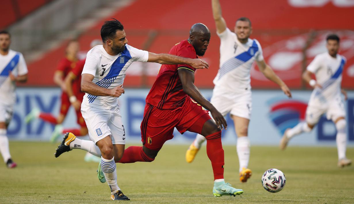 Striker Belgia, Romelu Lukaku, berebut bola dengan pemain Yunani, Giorgos Tzavellas, pada laga uji coba di Stadion King Baudouin, Jumat (4/6/2021). Kedua tim bermain imbang 1-1. (AP/Francisco Seco)