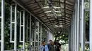 Pejalan kaki menyebrang di JPO Medan Merdeka Barat yang atapnya rusak di Jakarta, Jumat (19/1). Kondisi JPO yang penuh dengan genangan air dan atap yang rusak mengurangi kenyamanan bagi para pejalan kaki yang menggunakannya. (Liputan6.com/Johan Tallo)