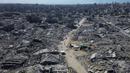 Foto udara yang diambil menggunakan pesawat tanpa awak atau drone memperlihatkan beberapa warga Palestina berjalan di sepanjang jalan yang dikelilingi oleh bangunan-bangunan yang hancur akibat serangan militer Israel selama dua tahun terakhir di Kota Gaza, Rabu 15 Oktober 2025. (AP Photo)