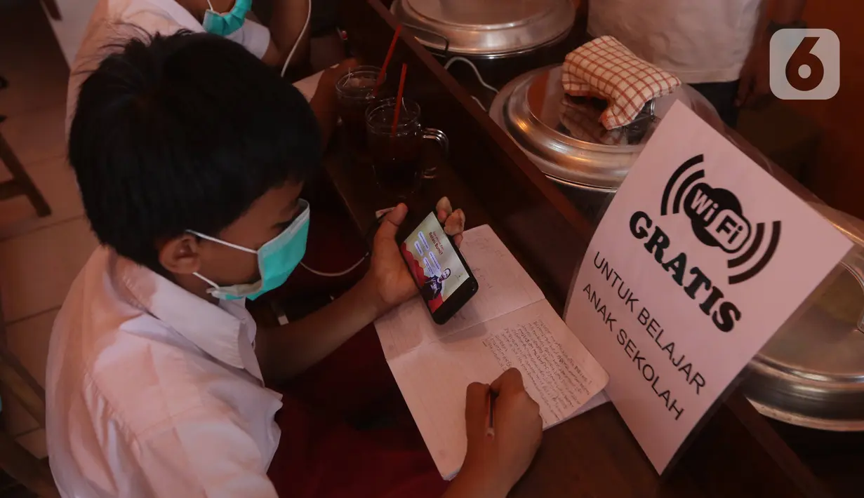Seorang siswa sekolah dasar belajar dengan menggunakan wifi gratis yang disediakan oleh warkop Rizki, di Pondok Aren, Tangerang Selatan, Rabu (29/7/2020). Warung kopi tersebut menyediakan wifi gratis dan peminjaman laptop serta handphone. (Liputan6.com/Angga Yuniar)
