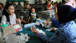Anggota TNI bersama istri dan anaknya mendaftar vaksinasi ulang di Kantor Kesehatan Kopassus, Jakarta, Senin (18/7). Kopassus menggelar vaksinasi ulang terhadap anak prajurit yang terindikasi menjadi korban vaksin palsu. (Liputan6.com/Helmi Afandi)