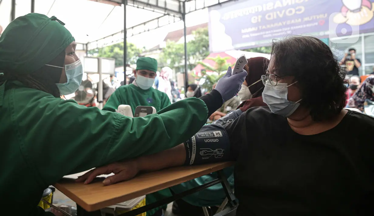 Tenaga kesehatan memeriksa kesehatan warga calon penerima vaksin COVID-19 dosis ketiga di Puskesmas Kecamatan Kramat Jati, Jakarta, Rabu (12/1/2022). Program booster COVID-19 diberikan kepada kelompok prioritas yaitu lanjut usia (lansia) dan penderita immunokompromais. (Liputan6.com/Faizal Fanani)
