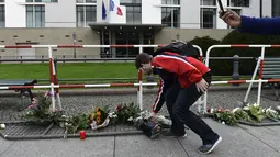 Seorang pria meletakkan bunga di luar Kedutaan Besar Perancis di Berlin, Sabtu (14/11/2015). Karangan bunga tersebut untuk menghormati para korban serangan mematikan di Paris. (AFP Photo/ Tobias Schwarz)