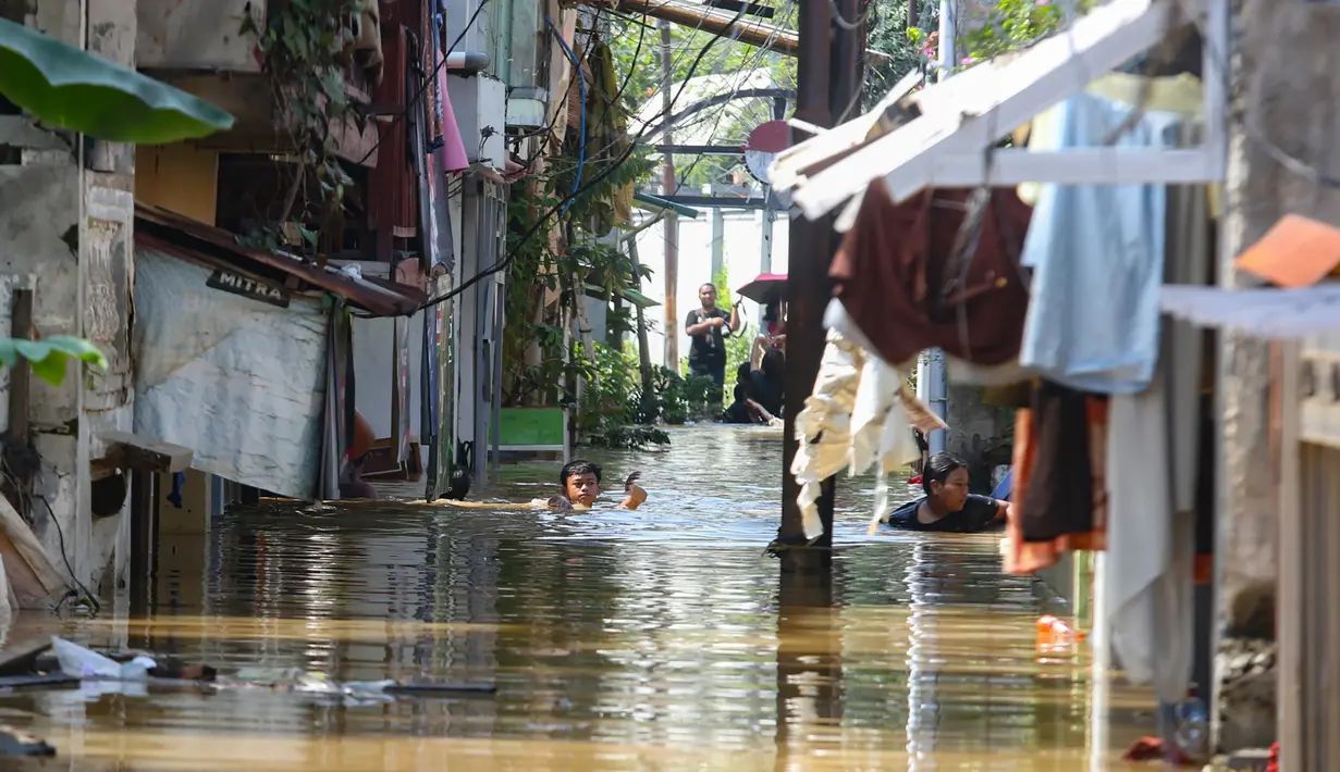 Warga beraktifitas saat banjir merendam pemukiman di Jalan Pirus, Kelurahan Bidara Cina, Jatinegara, Jakarta Timur, Minggu (6/7/2025). (merdeka.com/Arie Basuki)