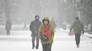 Seorang wanita berjalan saat salju turun di sebuah taman di Beijing (16/12/2019). Di sebagian besar wilayah kota, curah hujan rata-rata diperkirakan mencapai 5 hingga 8 milimeter. Angka itu bisa melebihi 10 mm, mencapai tingkat badai salju, di daerah tertentu di Beijing utara. (AFP Photo/Wang Zhao)