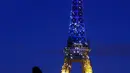 Warga melihat Menara Eiffel menyala dengan warna bendera Ukraina di Paris (25/2/2022). Pasukan Rusia menyerang ibu kota Ukraina pada Jumat (25/2) dengan tembakan dan ledakan dalam invasi ke negara demokratis yang memicu kekhawatiran perang yang lebih luas di Eropa. (AFP/ Thomas Coex)