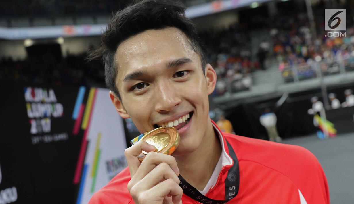 Pebulu tangkis putra Indonesia Jonatan Christie mengigit medali emas merayakan kemenangan pada final tunggal putra SEA Games 2017 melawan Khosit Phetpradab dari Thailand di Axiata Arena, Malaysia, Selasa (29/8). (Liputan6.com/Faizal Fanani)