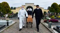 Pengusung jenazah membawa peti mati seorang warga yang meninggal akibat virus corona untuk upacara pemakaman tanpa kehadiran dari sanak saudaranya yang sedang menghadapi karantina selama masa lockdown di pemakaman Grassobbio, Lombardy, Italia, Senin (23/3/2020). (Piero CRUCIATTI / AFP)