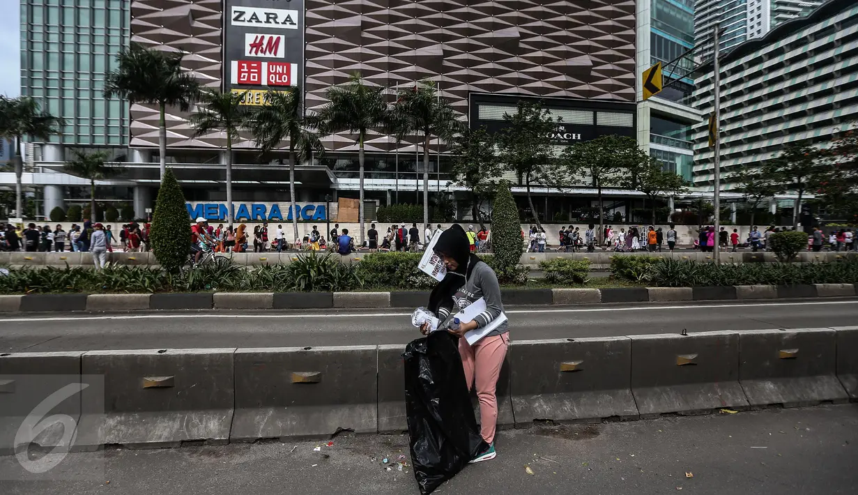 Seorang wanita dikenakan sanksi memunguti sampah arena di car free day (CFD) Bundaran HI, Jakarta, Minggu (29/1). Sejumlah pengunjung terjaring operasi tangkap tangan (OTT) karena membuang sampah sembarang di arena CFD. (Liputan6.com/Faizal Fanani)