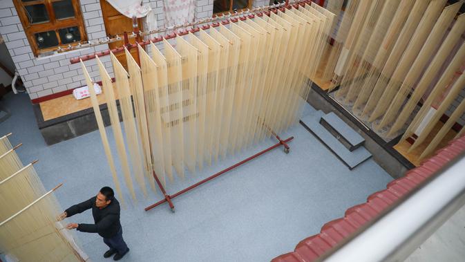 Seorang penduduk desa mengeringkan mi di Desa Huangjiazhuang di Distrik Maiji, Kota Tianshui, Provinsi Gansu, China barat laut, pada 30 November 2020. Proses pembuatan mi di desa tersebut memiliki sejarah lebih dari 200 tahun. (Xinhua/Ma Xiping)
