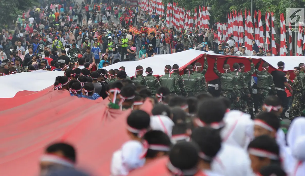 Anggota TNI POLRI  bersama warga masyarakat membawa bendera raksasa berukuran panjang 117 meter dan lebar 5 meter saat gelaran Festival Merah-Putih (FMP) 2018 di kawasan Air Mancur, Bogor ,  Minggu (5/8). (Merdeka.com/Arie Basuki)