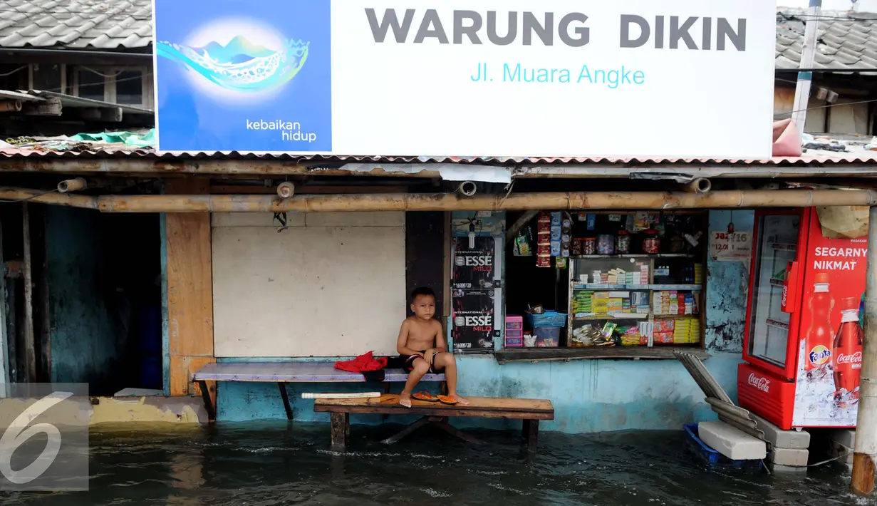 Seorang anak duduk di depan rumahnya yang tergenang air di Kawasan Muara Angke, Jakarta, Rabu (11/1). Banjir yang terjadi hampir setiap hari dalam satu bulan terakhir akibat rob yang diperparah dengan jebolnya tanggul. (Liputan6.com/Gempur M. Surya)