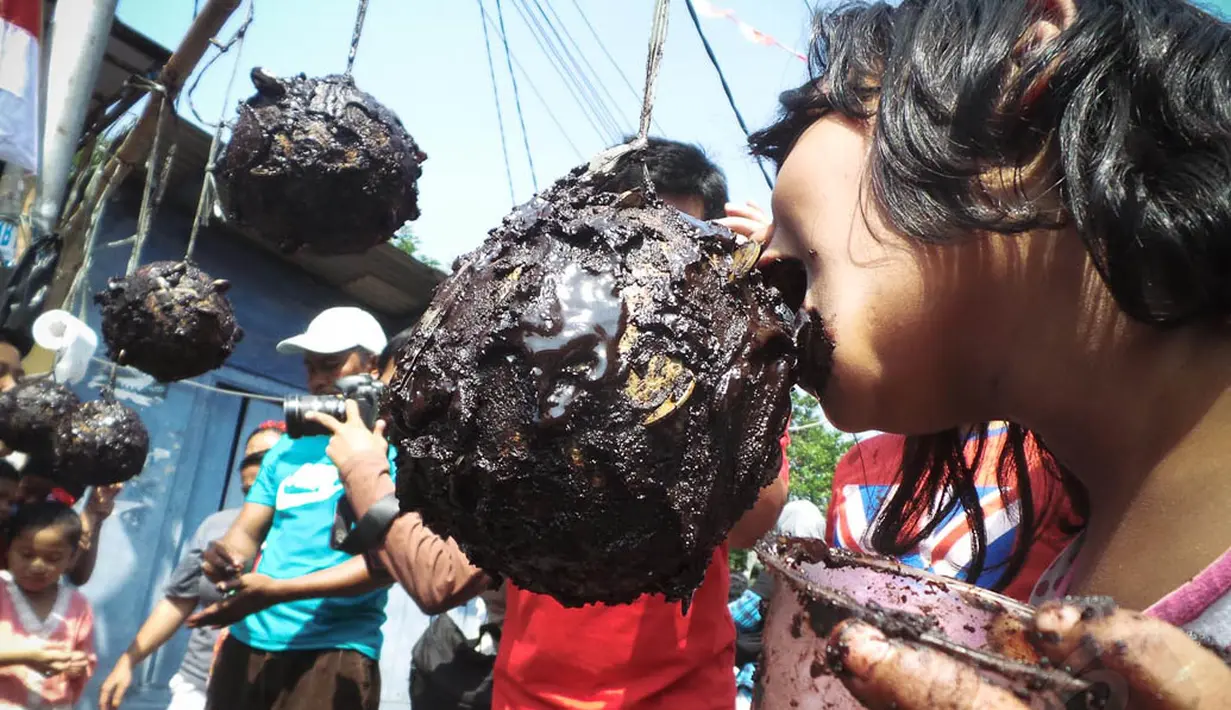 Seorang anak terlihat berusaha mengambil koin yang diberi cat warna hitam saat perlombaan dalam rangka perayaan HUT RI ke-69, Jakarta, Minggu (17/8/14). (Liputan6.com/Faizal Fanani) 