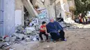 Warga Palestina duduk di tengah puing-puing setelah serangan udara Israel di Rafah, Jalur Gaza, Palestina, 19 Mei 2021. Serangan udara Israel terus mengguncang Gaza di tengah dorongan diplomatik internasional untuk menengahi gencatan senjata. (SAID KHATIB/AFP)