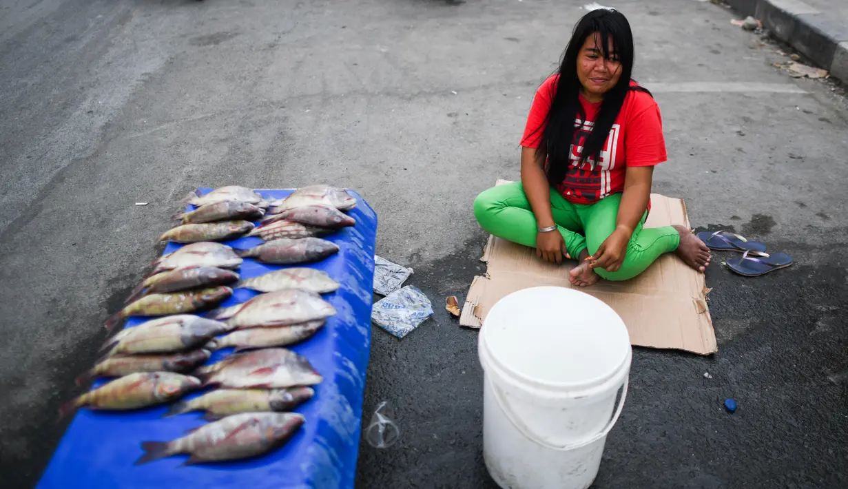 Pedagang menunggu pembeli saat menjajakan ikan dagangannya di sebuah pasar tradisional usai gempa dan tsunami melanda Palu, Sulawesi Tengah, Kamis (4/10). Kebanyakan pedagang berjualan kebutuhan pokok. (Permata SAMAD/AFP)