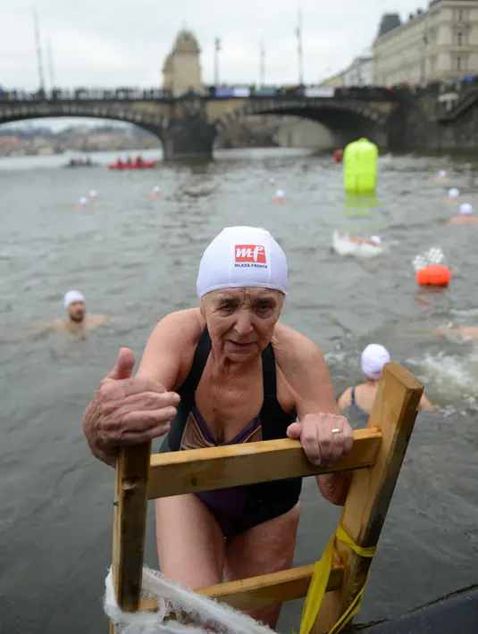 Bozena Cerna (88) keluar dari sungai Vltava setelah mengikuti kompetisi berenang Natal tahunan, di ibu kota Republik ceko, Praha, Rabu (26/12). Dalam menyemarakkan Natal, mereka mengikuti lomba renang di sungai bersuhu dingin. (Michal CIZEK / AFP)